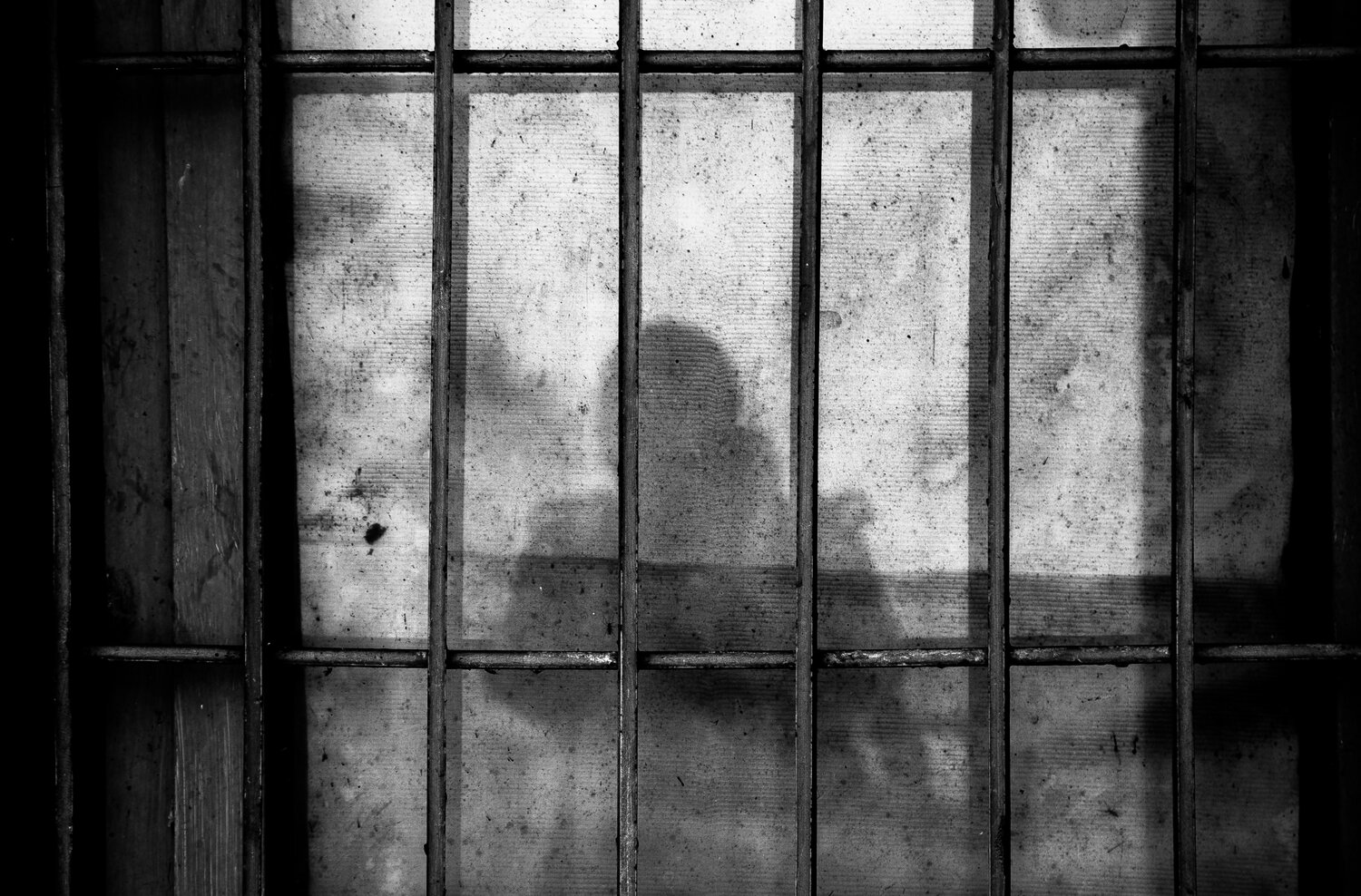 Shadow of a person through jail bars